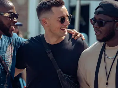 Four people standing in row with arms around shoulders