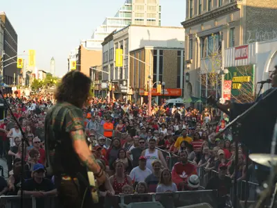 Photo of performer playing guitar on stage with crowd in the background